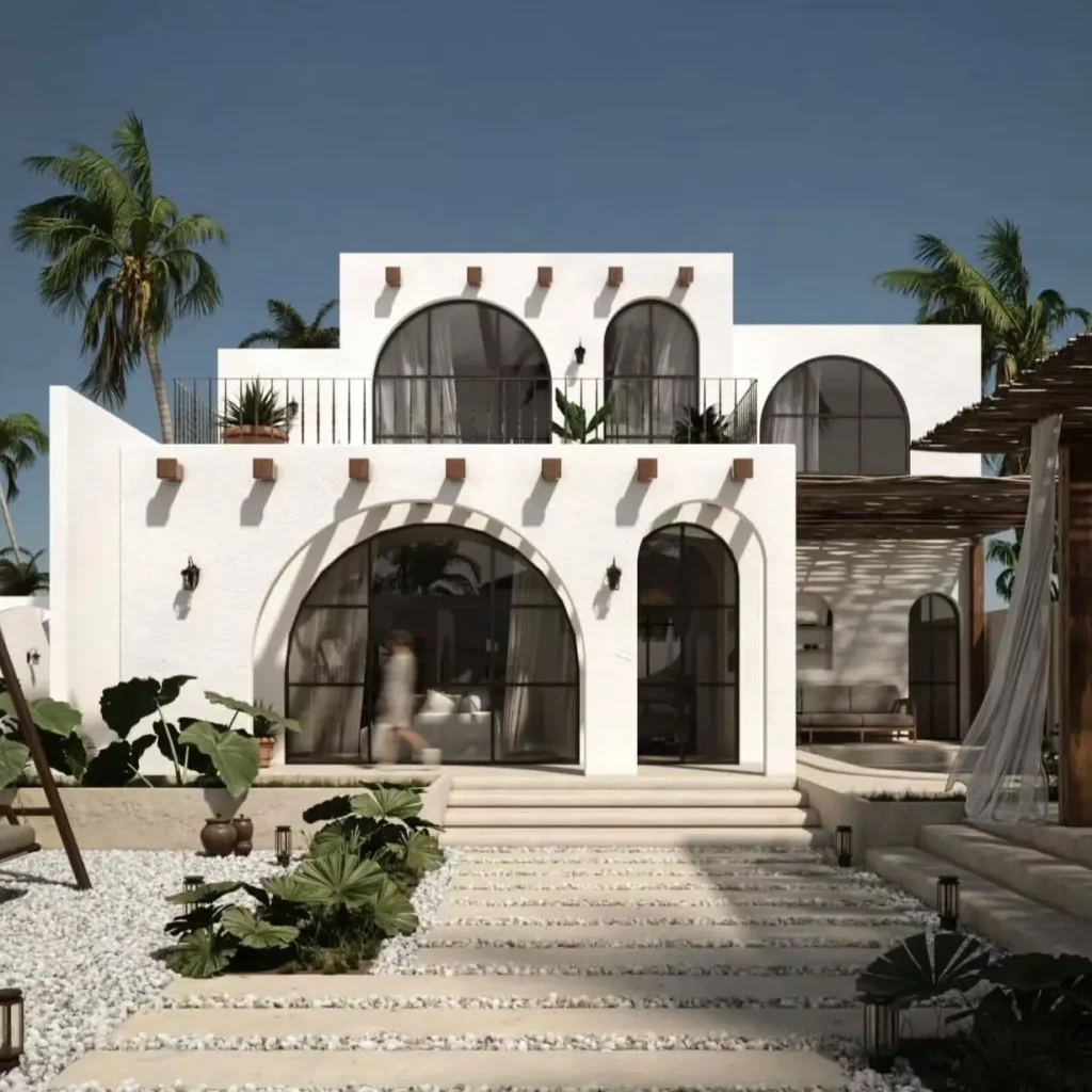 A modern white Mediterranean home with large arched windows, black frames, and a gravel walkway.