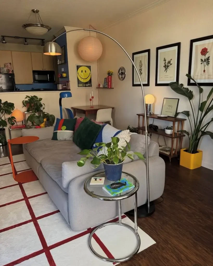 An eclectic living room showcasing a cozy small apartment interior design with a mix of modern furniture, botanical prints, and retro accents.