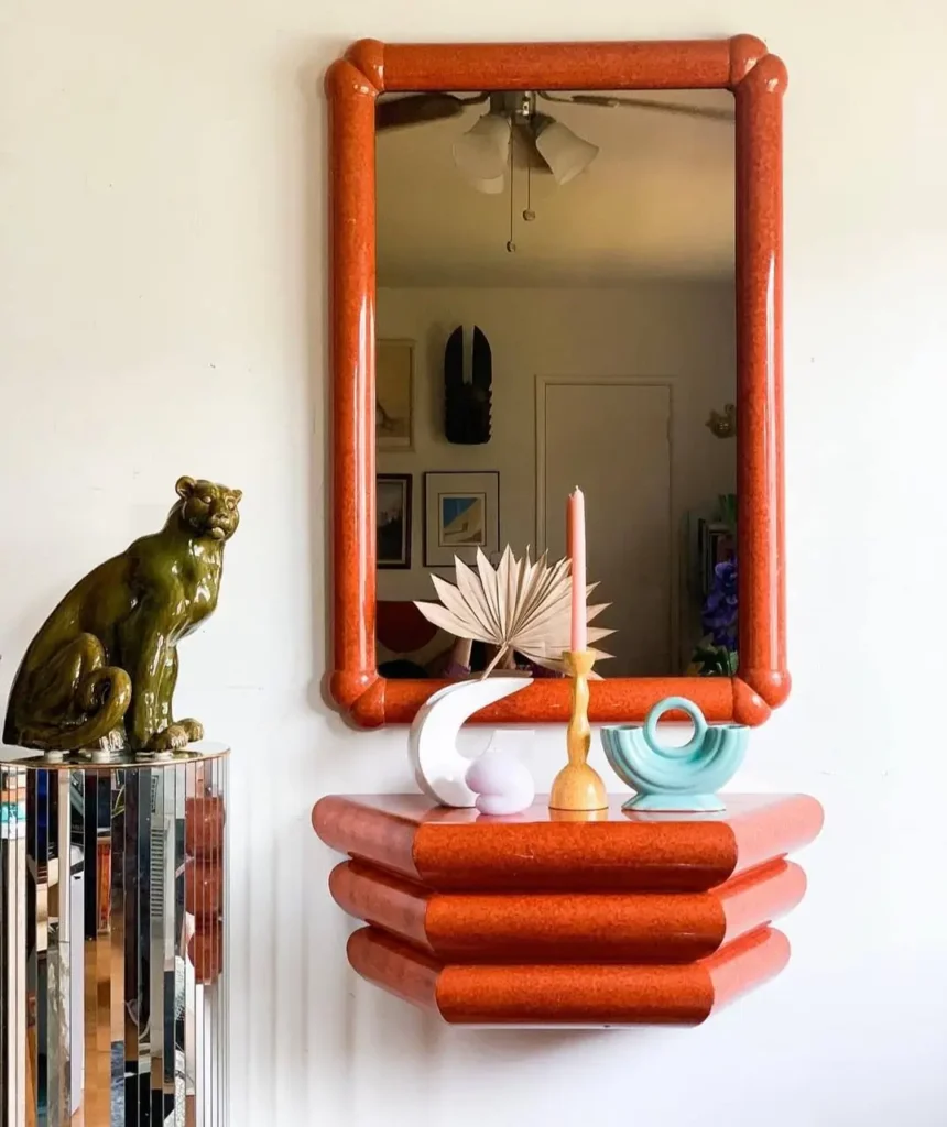 Chunky orange mirror and shelf set, showcasing 70s interior decor and a mirrored pedestal.