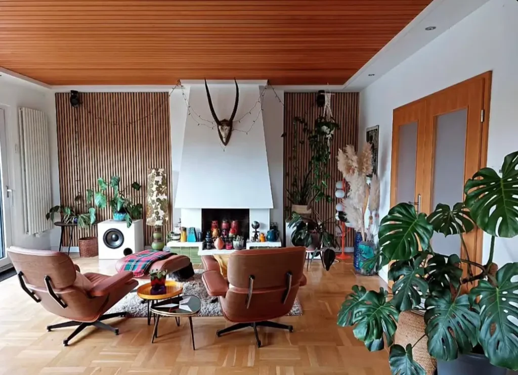 A 70s living room with wood slat accent walls, a white modern fireplace, and two lounge chairs.