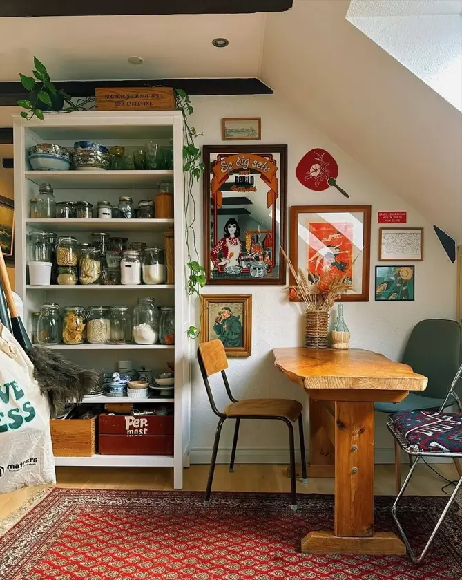 A cozy small apartment dining nook with a well-organized pantry wall, a rustic wooden table, and an eclectic gallery wall.