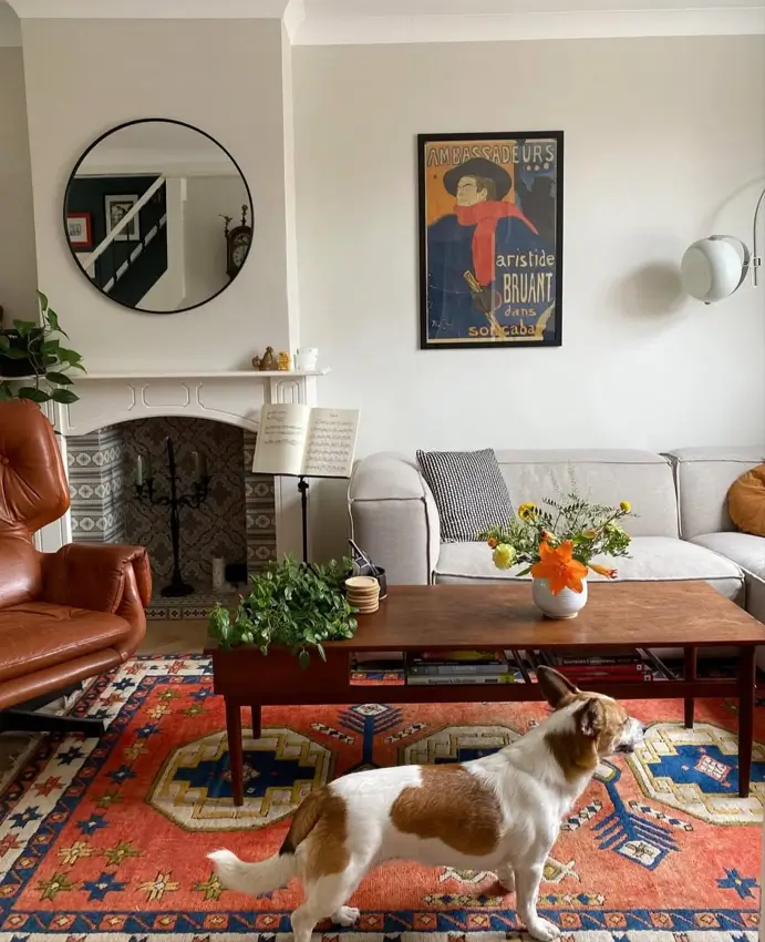 A modern living room with a white sofa, a large 70s-style geometric rug, and a brown leather chair.