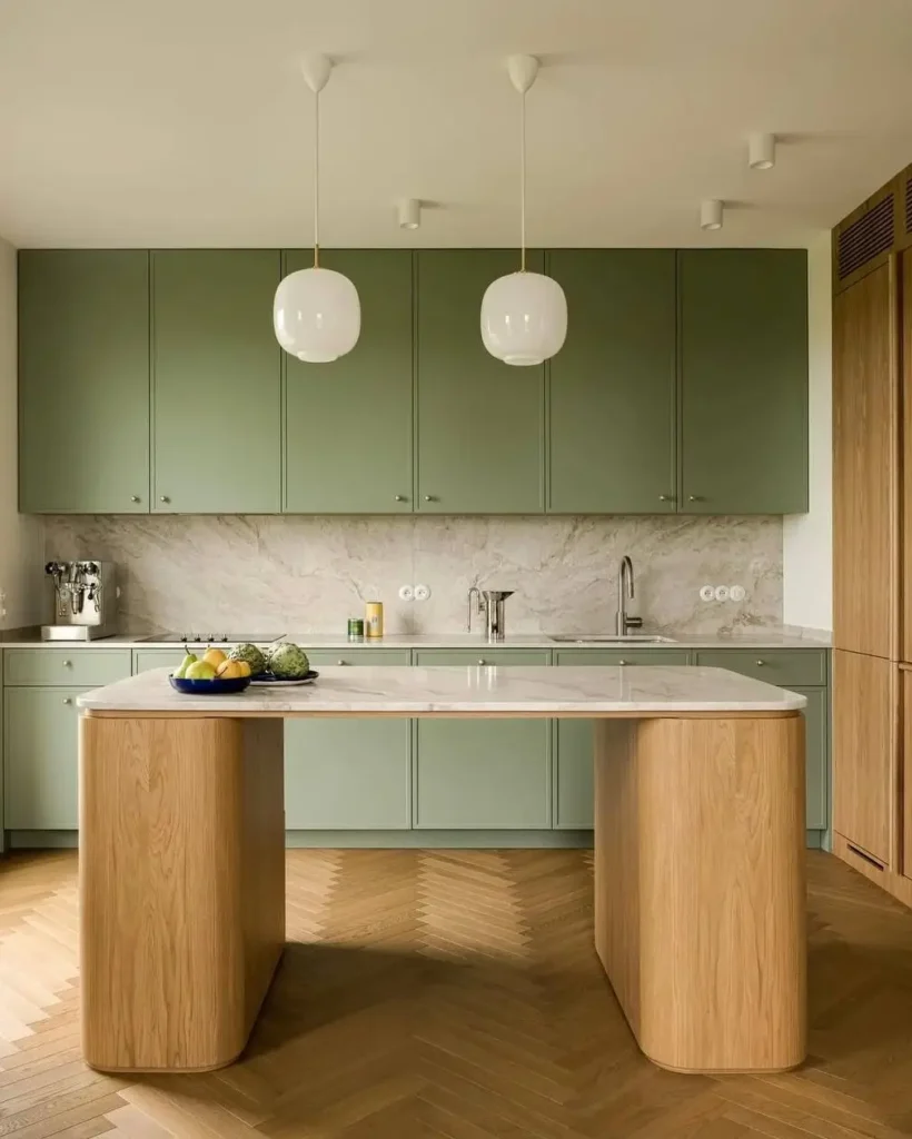 Modern minimalist kitchen by Klara Ostrowska Studio with a sculptural curved wood island and sage green cabinets.