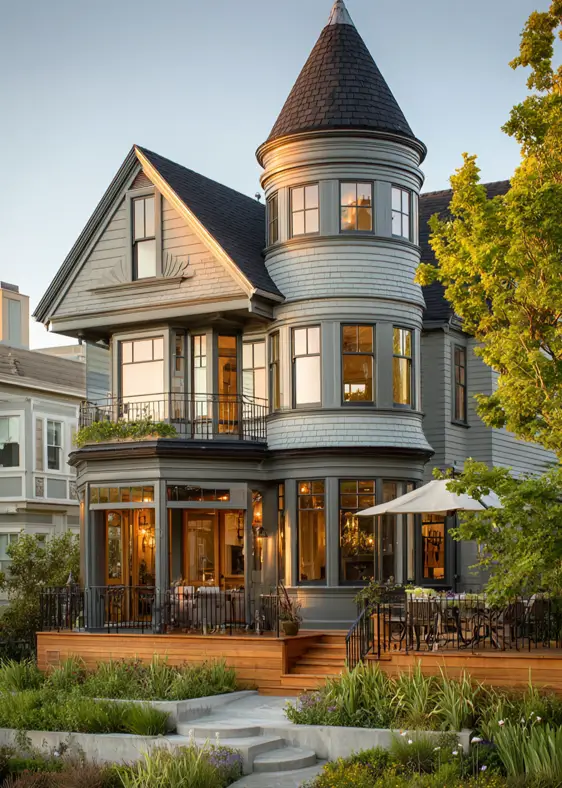 A restored modern Victorian style home with sage-green siding and a large wooden deck for outdoor living.