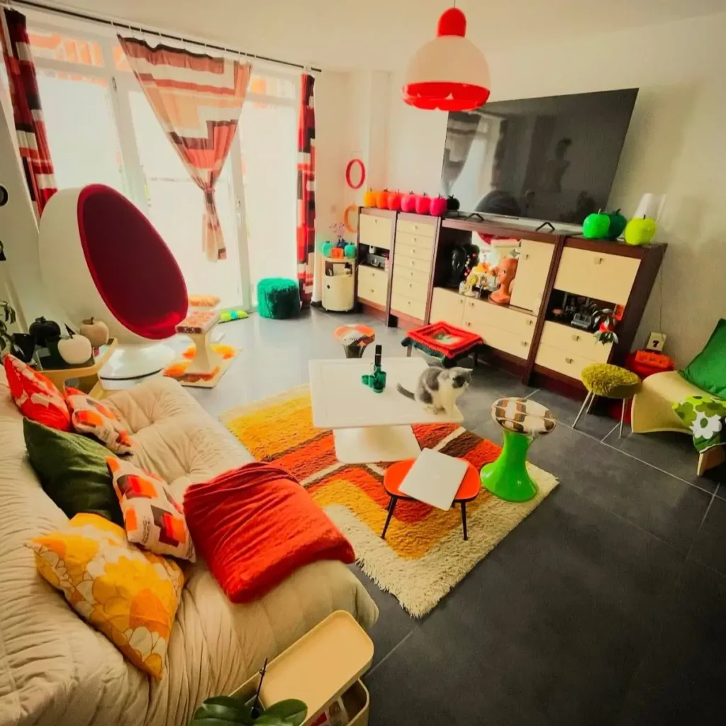 A 70s living room with a white ball chair, a red pendant lamp, and a colorful shag rug.