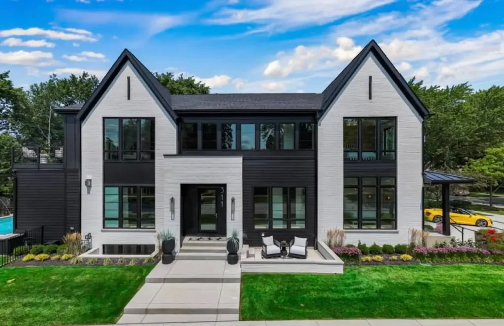 A symmetrical modern farmhouse using graphic color-blocking with white brick and black siding for a high-contrast look.