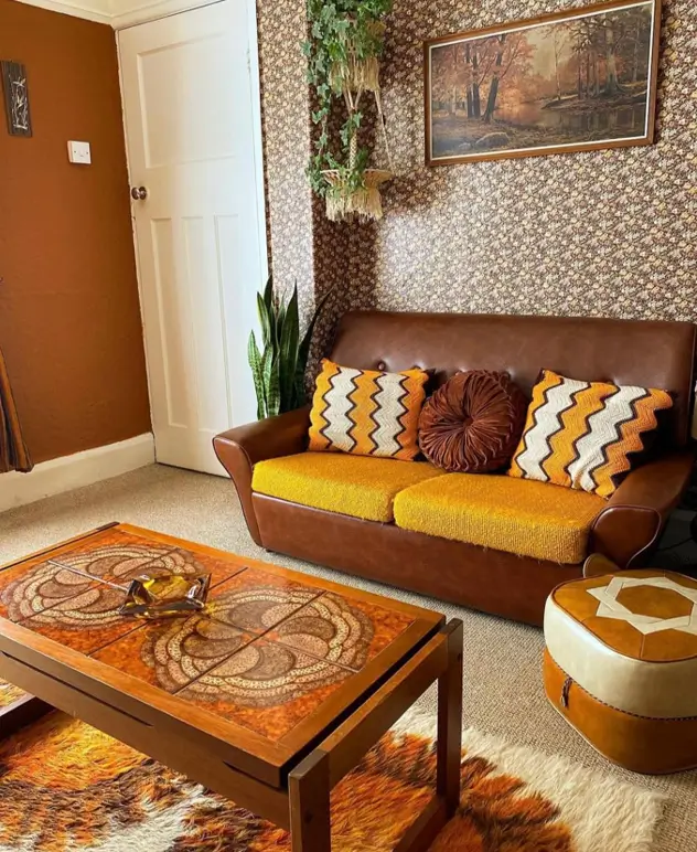 A 70s living room corner with a brown and yellow sofa, graphic pillows, and floral wallpaper.