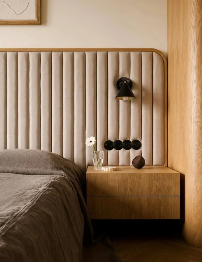 Minimalist bedroom detail by Klara Ostrowska Studio, featuring a tall, soft upholstered headboard.