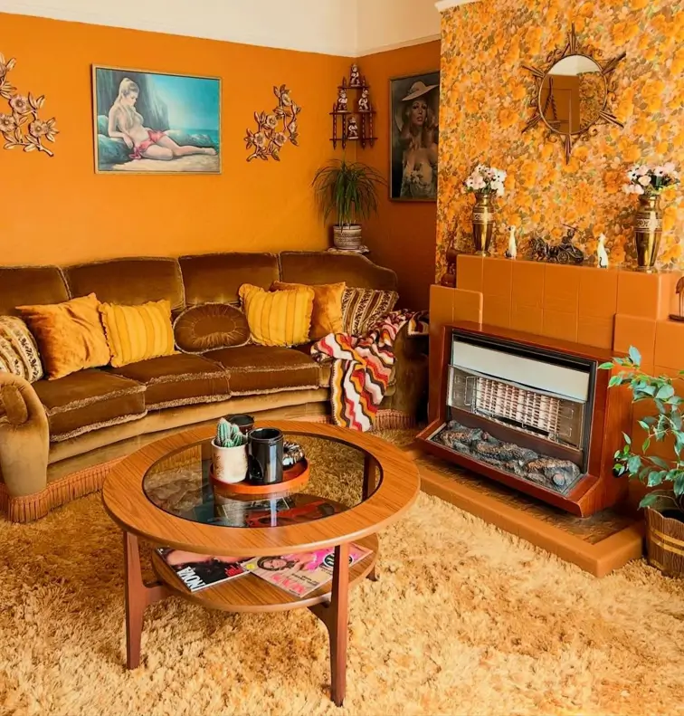 A 70s retro living room with a brown velvet sofa, gold shag carpet, and floral wallpaper.