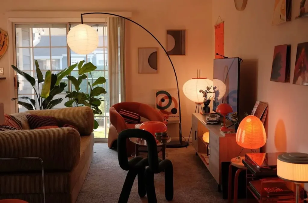 A cozy small apartment living room with layered lighting from multiple lamps, creating a warm and inviting interior atmosphere at dusk.