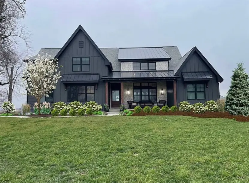 A modern black farmhouse exterior with a central limewashed brick accent wall on the front porch.