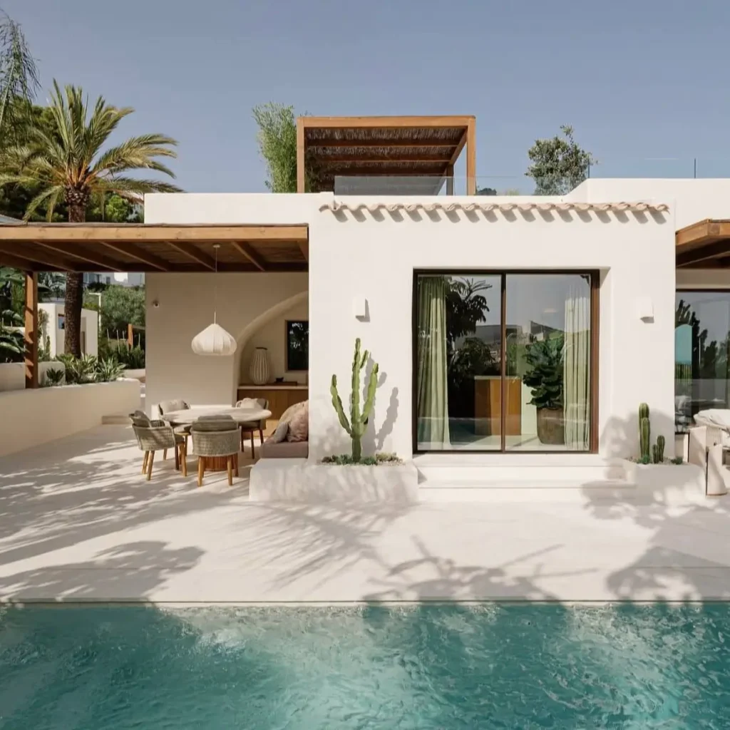 A modern white Mediterranean house with wooden pergolas, a minimalist patio, and a pool.
