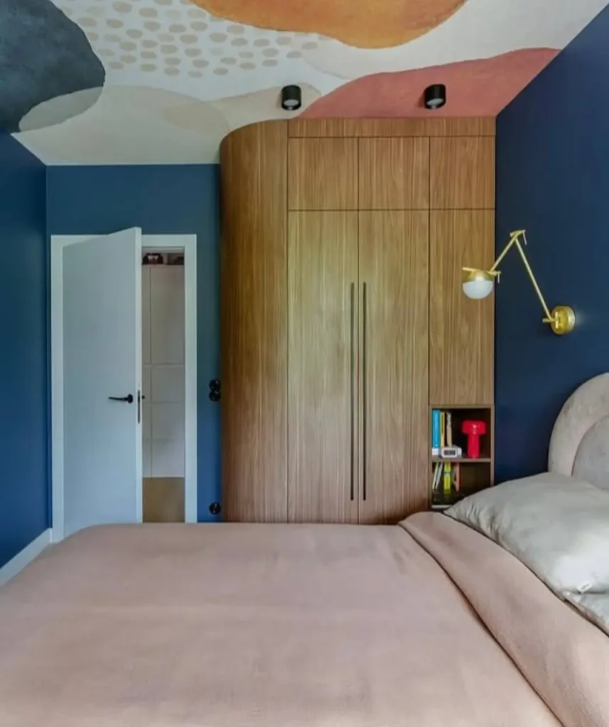 Minimalist bedroom by Projektive Architekci with deep blue walls and a custom curved wood wardrobe.
