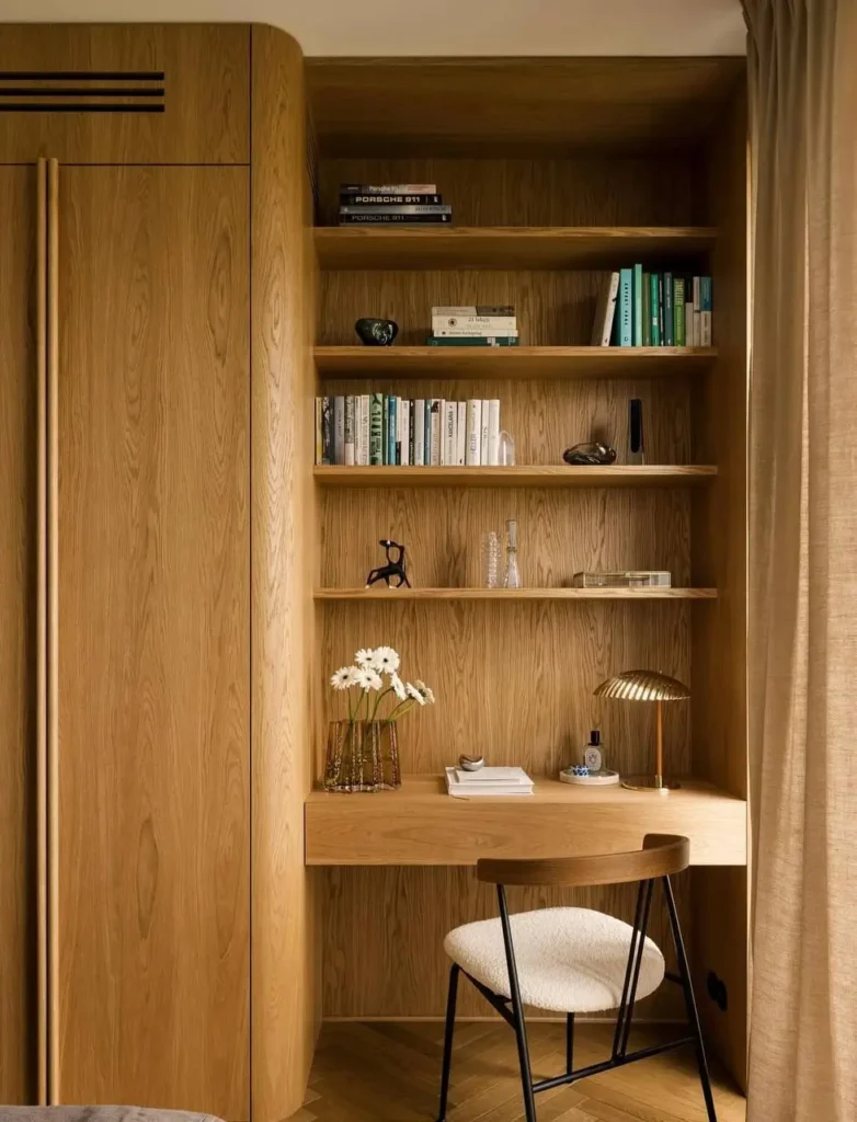 A minimalist home office by Klara Ostrowska Studio with sculptural, rounded wood built-ins.