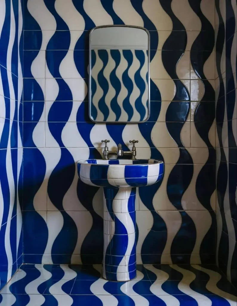 A retro 70s bathroom fully tiled in a blue and white graphic wave pattern, including the pedestal sink.