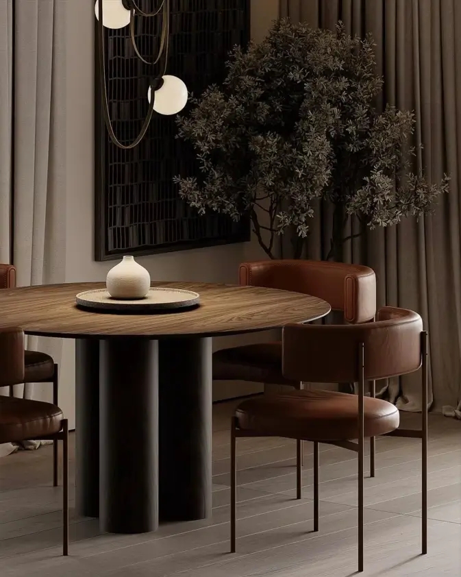 A sophisticated condo dining area with a round, dark wood table featuring a columnar base, paired with modern brown leather chairs.