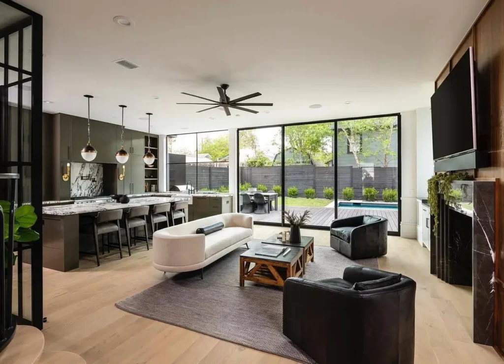 An open-plan modern Victorian interior showing the living room, kitchen, and large glass doors to the backyard.