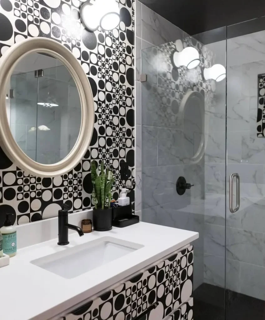 A modern 70s bathroom featuring a bold black and white geometric op-art pattern on the wall and vanity.
