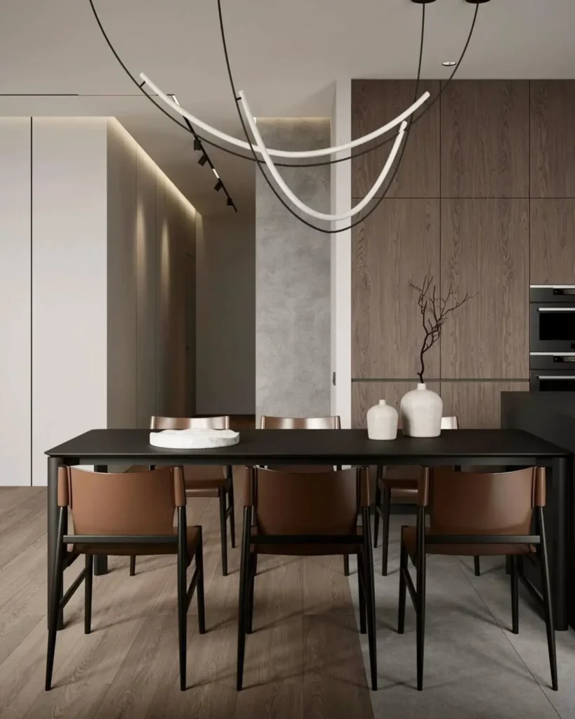 A sleek rectangular black condo dining table with brown leather chairs under a sculptural light fixture in a modern dining room.