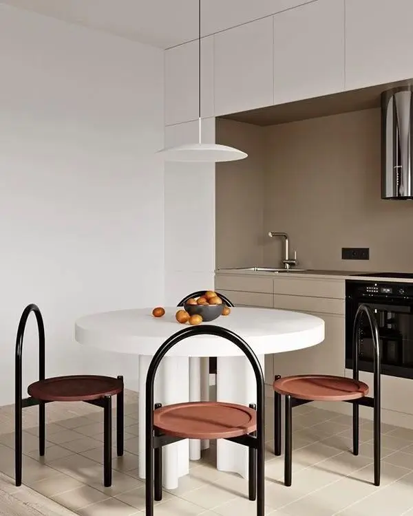 A small condo dining room idea featuring a minimalist white table with unique, artistic chairs with black frames and terracotta seats.