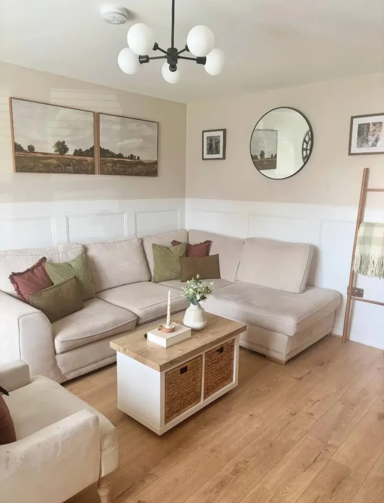 A cozy, warm neutral living room with a beige sectional, a coffee table with wicker basket storage, and white wall paneling.