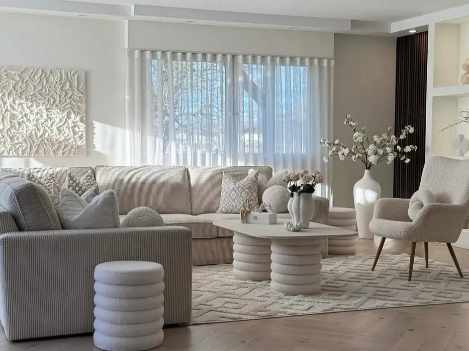 A sunlit, modern neutral living room featuring a corduroy sectional, bouclé armchair, and textured white art, showcasing sophisticated decor ideas.