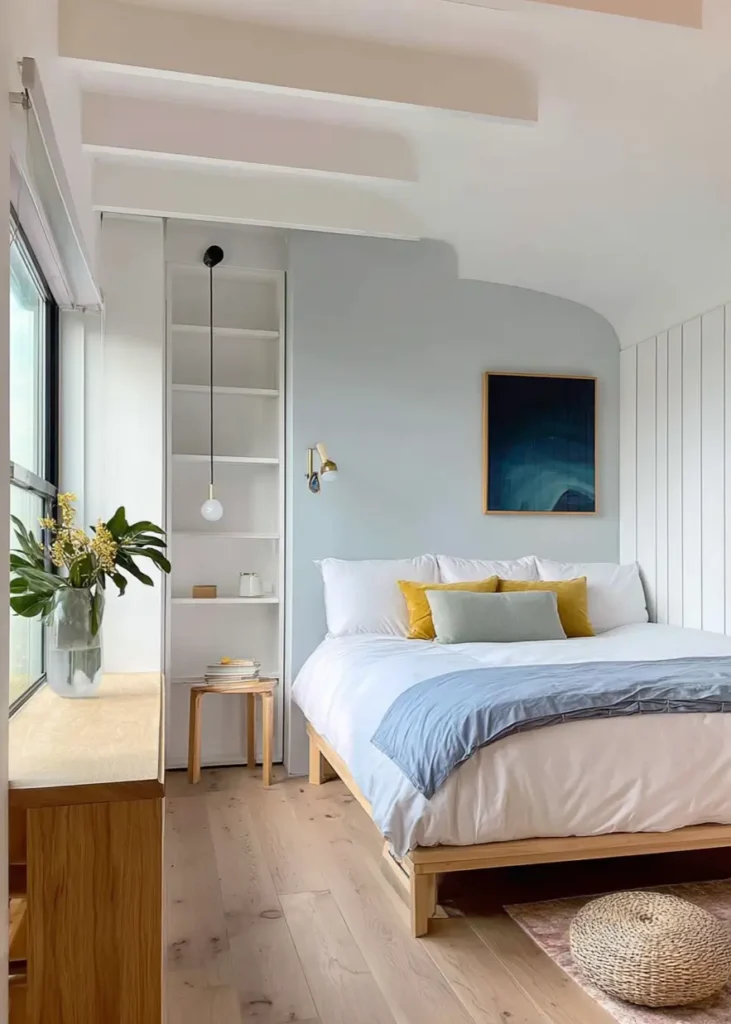 47 Scandinavian Bedroom Interior Design Ideas for a Serene Retreat 3 A modern Scandinavian bedroom with pale blue walls, light wood floors, and built-in white shelving.