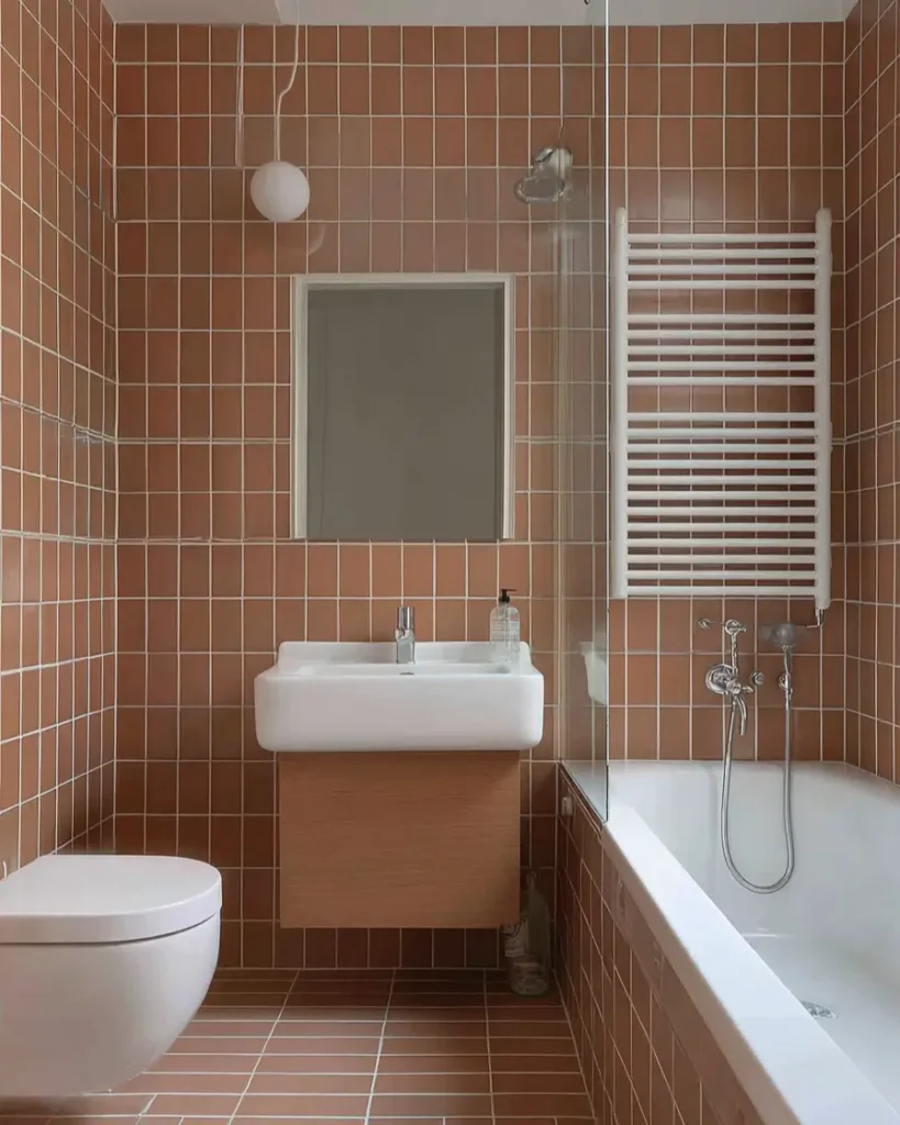 A contemporary Scandinavian bathroom with floor-to-ceiling terracotta grid tiles, white fixtures, and a light wood vanity.