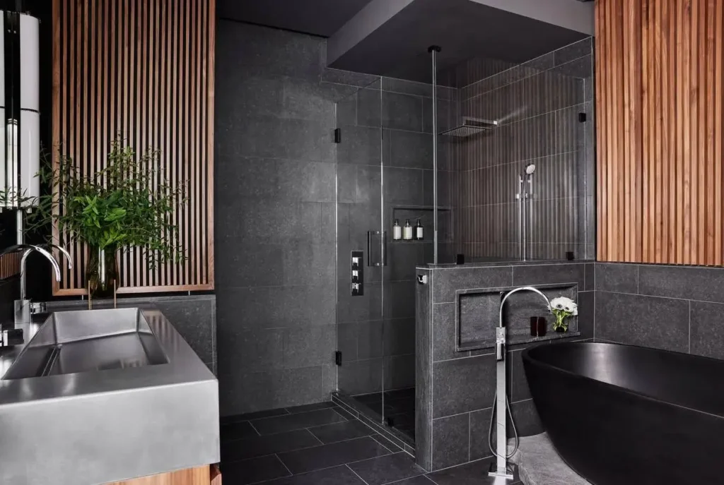 26 Japanese Bathroom Design Ideas for a Serene Home Oasis 12 A dark, modern Japanese inspired bathroom with stone tiles, wood slat walls, and a black freestanding tub.