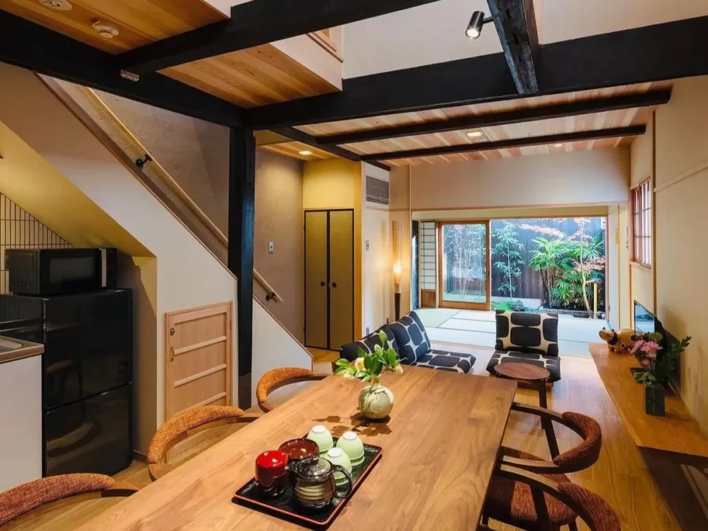Open-plan Japanese living room and dining area with exposed dark beams and a view of a garden.