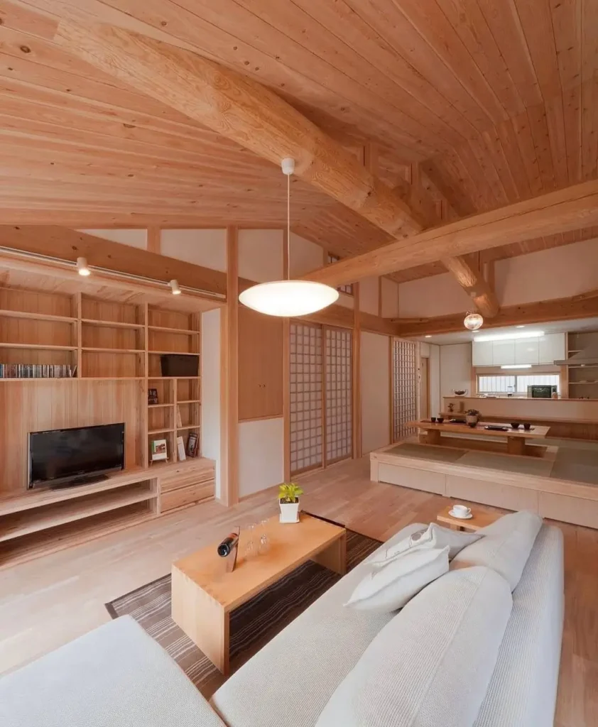 A modern Japanese home interior design idea, with a living room enveloped in light wood, featuring a sofa and built-in shelving.