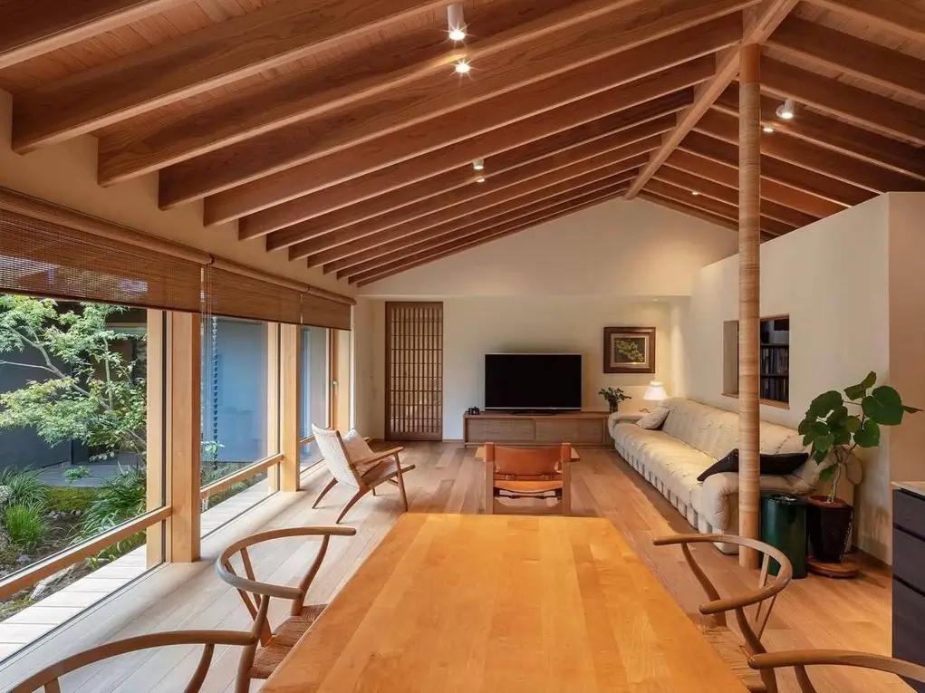 Bright Japanese living room with a vaulted wood ceiling and large windows overlooking a garden.