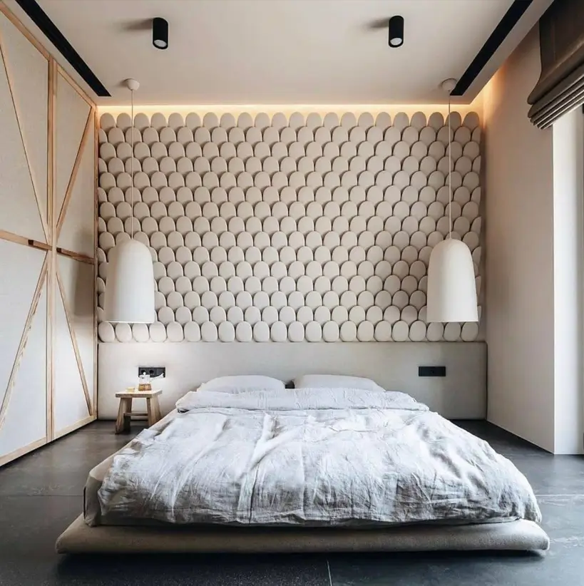 A modern bedroom with a 3D sculptural feature wall, a low platform bed, and minimalist pendant lights.