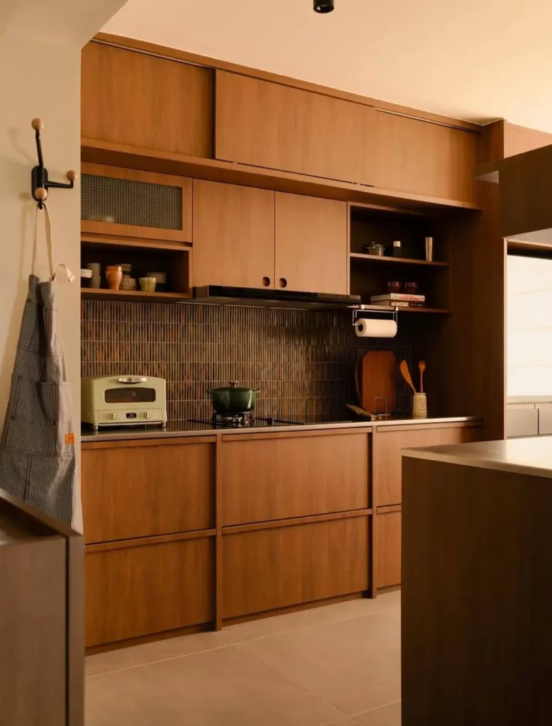 A modern Japanese-style kitchen with warm wood cabinets and a dark, vertically stacked tile backsplash.
