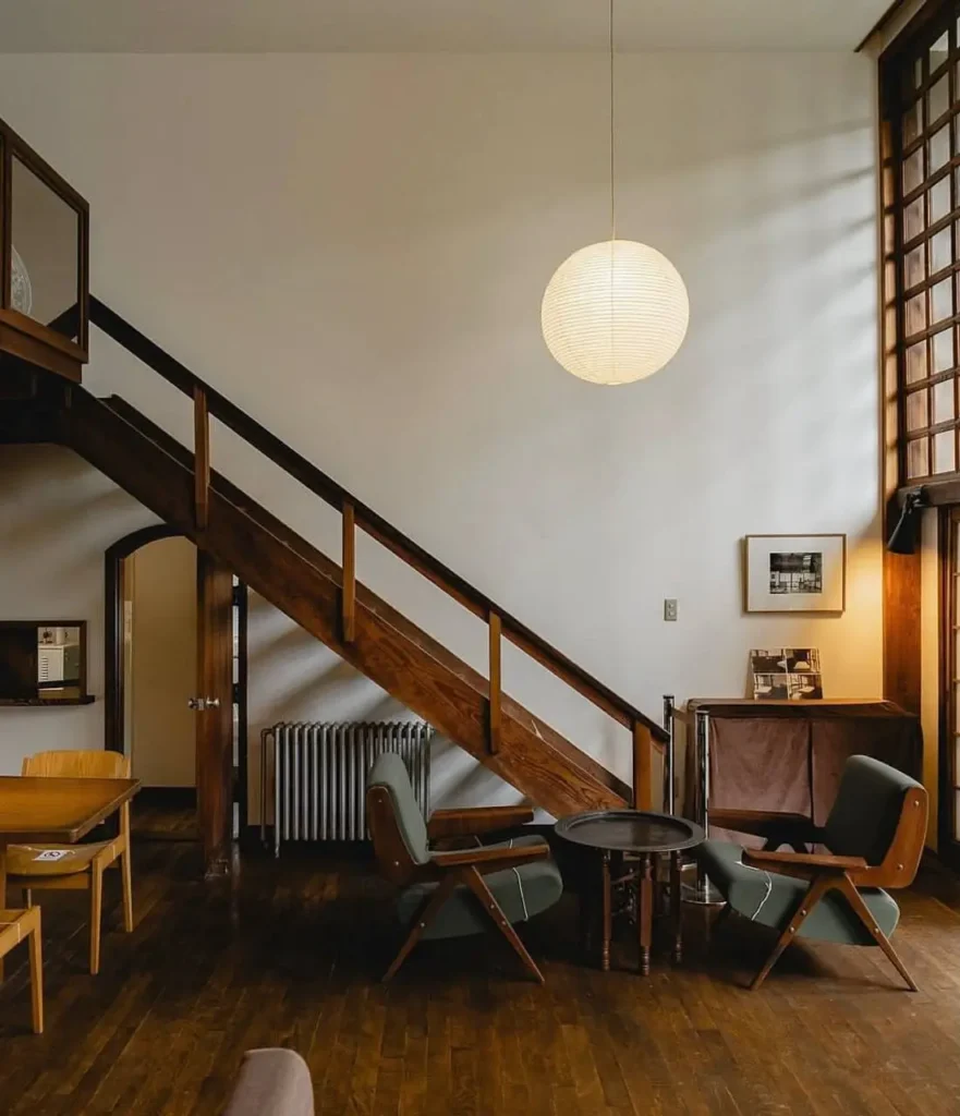 A Japanese-style sitting area with dark wood floors, a staircase, and a tall lattice window.