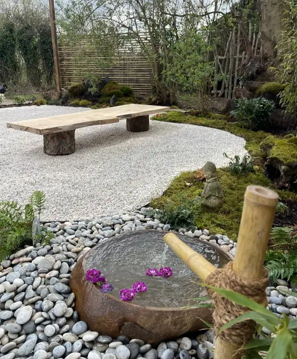 Zen garden design with a bamboo water feature, stone basin, and a simple wooden bench.