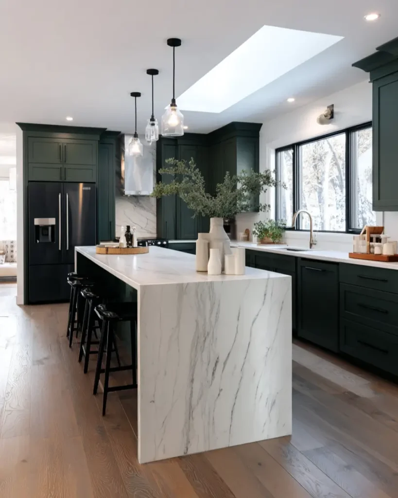 Modern kitchen with deep green cabinetry and a contrasting white marble waterfall island.