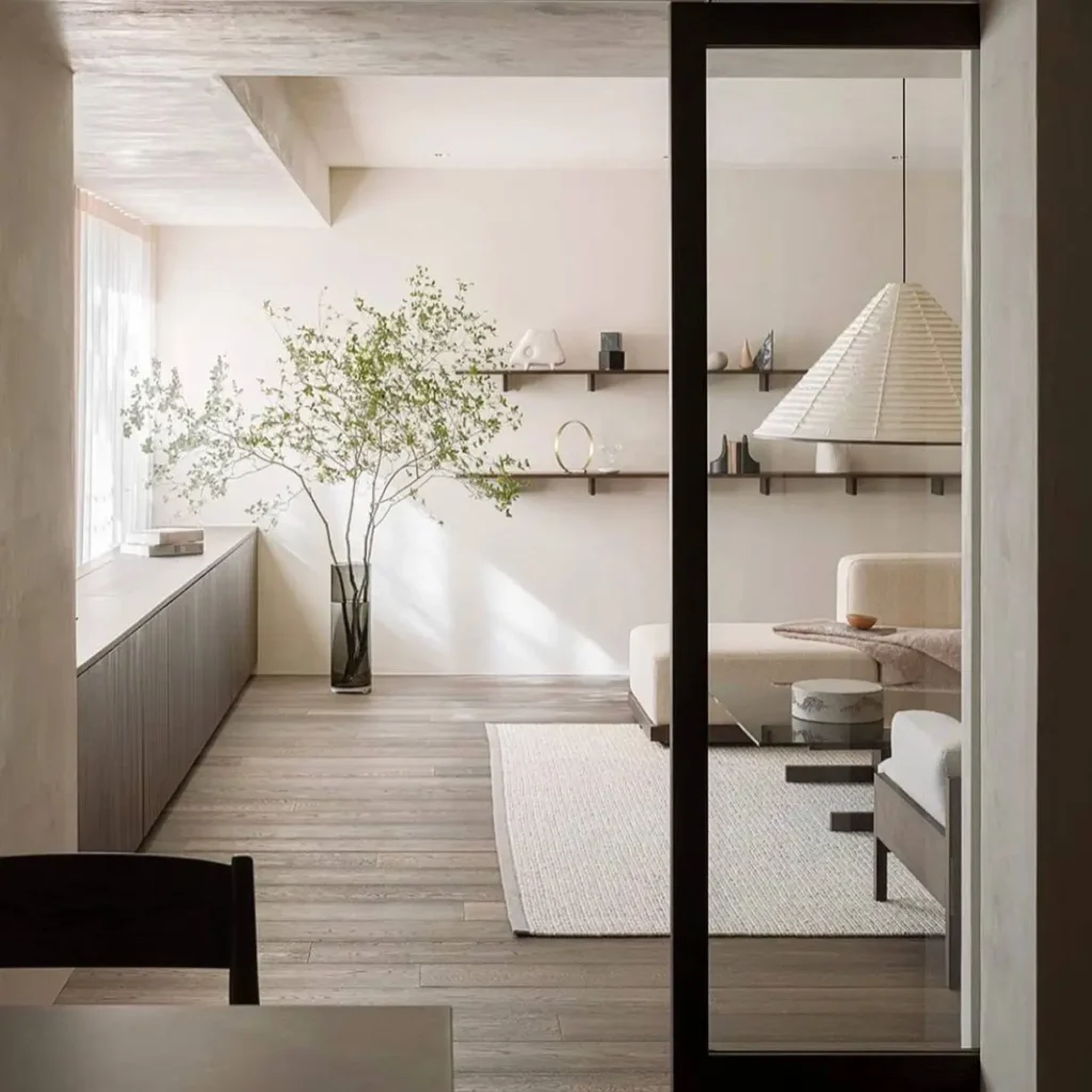 Bright, minimalist living room with a sculptural paper pendant light and curated shelving.