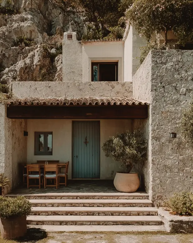 38 Small Mediterranean-Style Homes That Define Coastal Charm 17 Stone hillside small Mediterranean-style home retreat with rough-hewn walls and a shaded timber porch and patio.