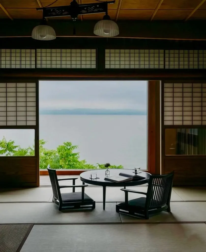 A traditional Japanese room with shoji screens opening to a wide water view, an example of shakkei.