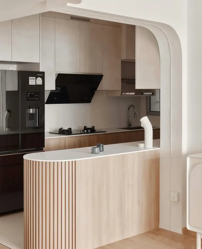 A Japanese inspired kitchen with a fluted light wood peninsula and a white architectural archway.