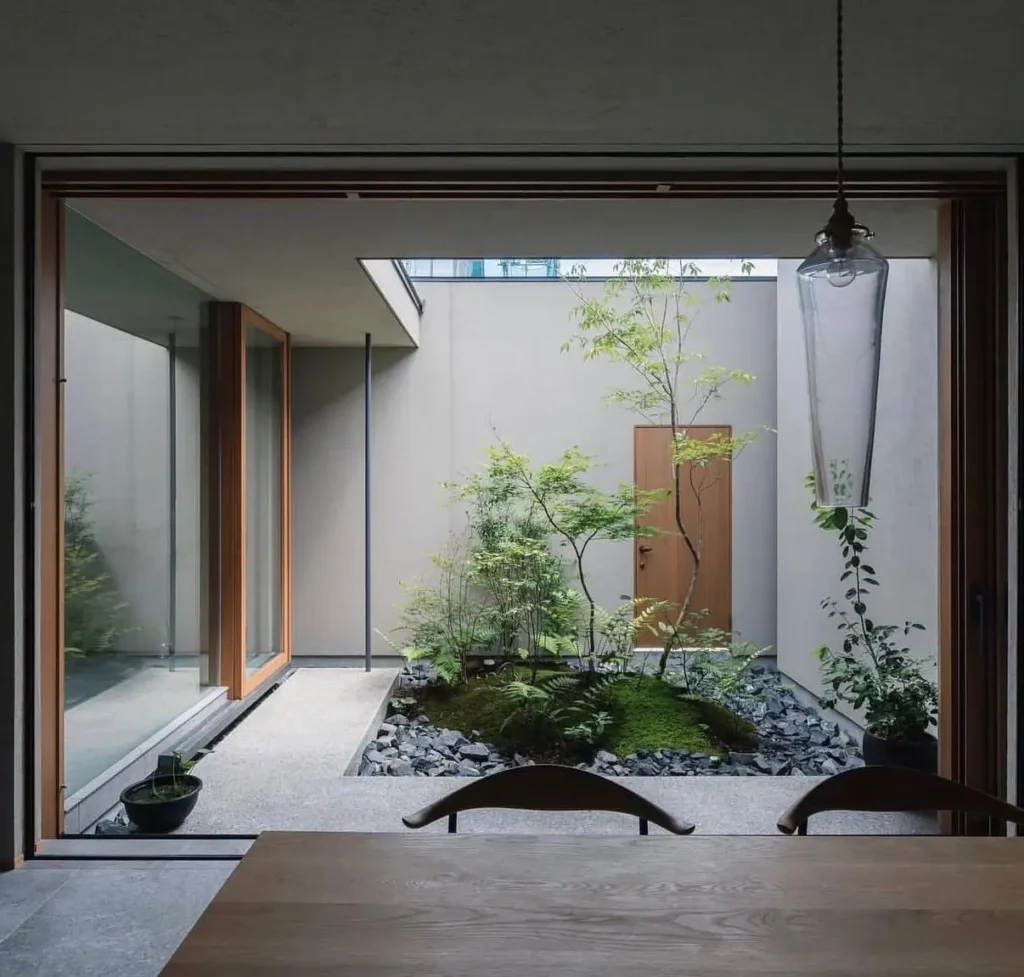 A modern Japanese home's dining room looking out onto a central tsuboniwa garden courtyard.