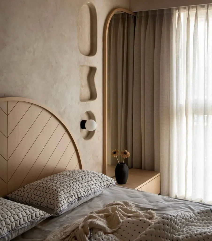 A modern Japandi bedroom with a textured plaster wall, built-in niches, and a light wood patterned headboard.