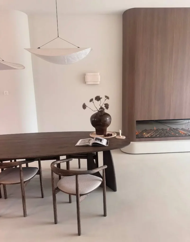 A modern Japandi dining room with a dark wood table, curved chairs, and a sculptural paper pendant light.