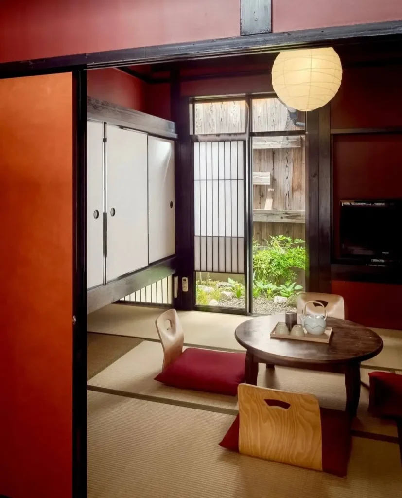 A traditional Japanese interior home design with red and black walls, tatami floors, and a garden view.