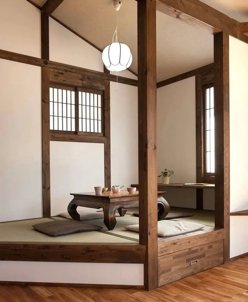 A raised Japanese tatami room, part of a traditional Japanese interior home design, with dark wood framing and a low table.