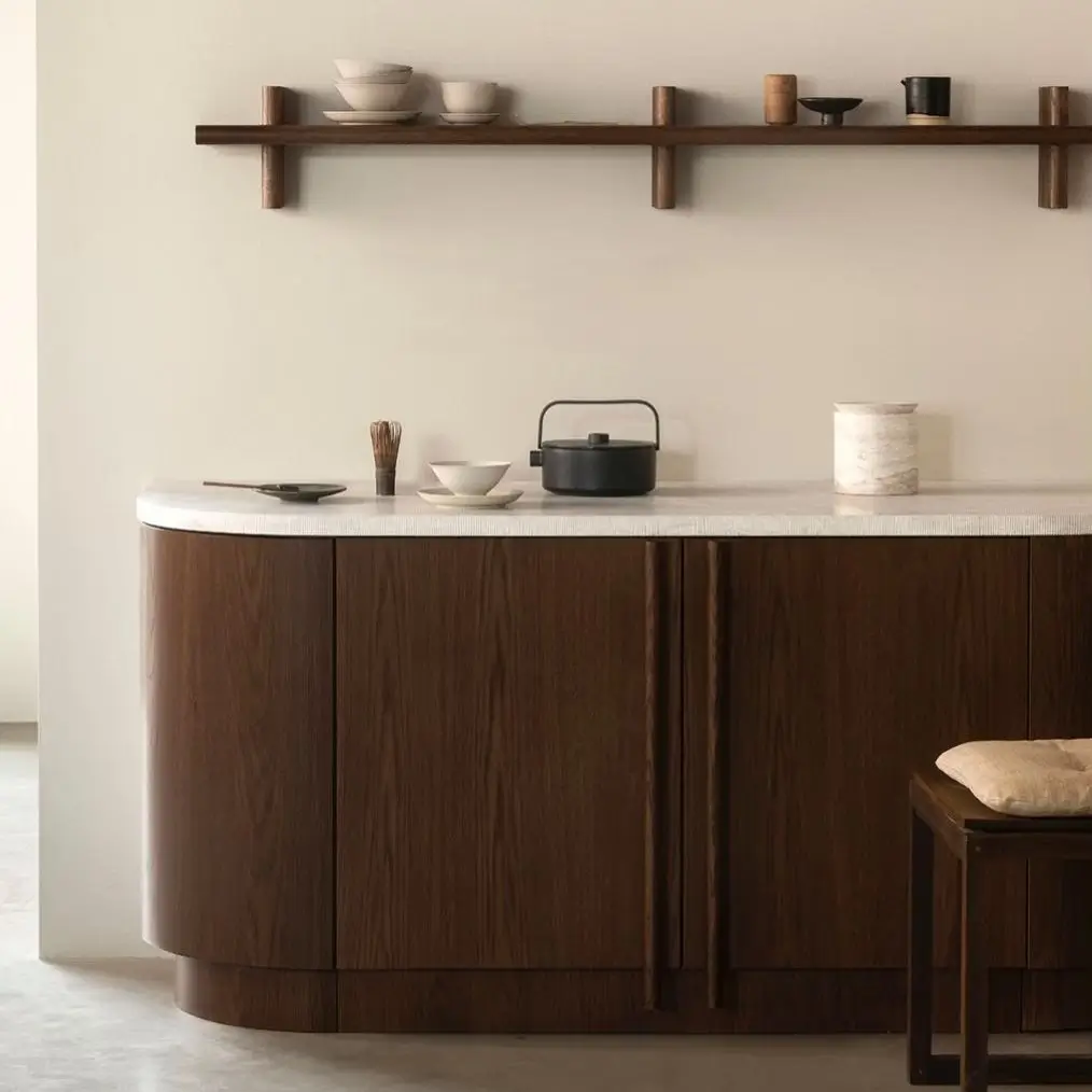 A dark wood Japanese style kitchen cabinet with a marble top and a simple wall shelf holding a tea set.