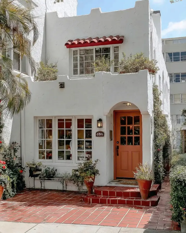 38 Small Mediterranean-Style Homes That Define Coastal Charm 4 Small Mediterranean house design with crisp white stucco walls, terracotta tile steps, and a warm wood entry door.