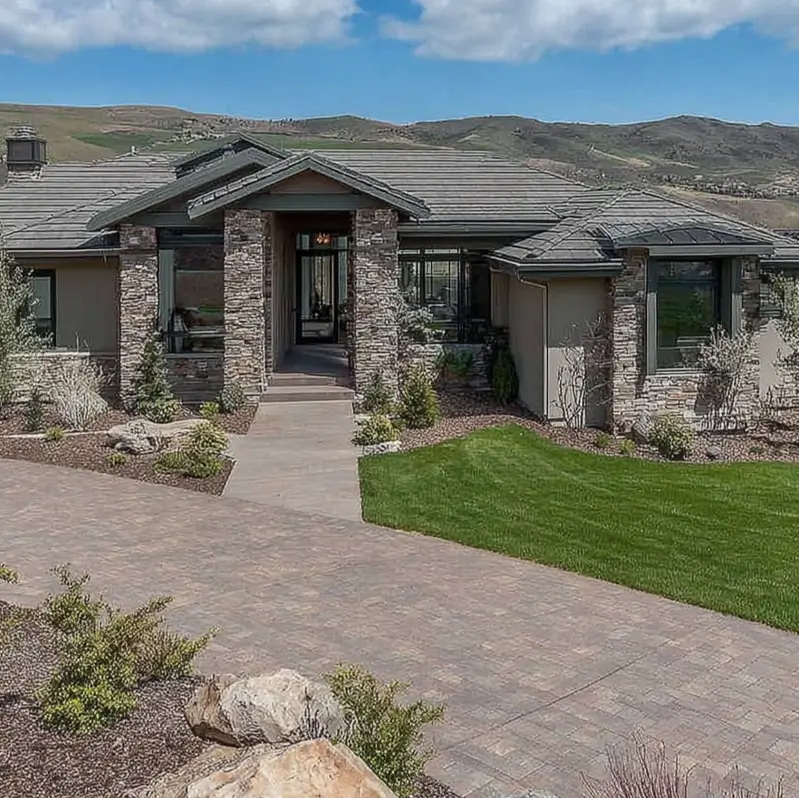 A sprawling modern ranch style house with a stone exterior and hipped roof.