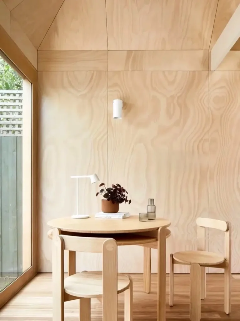 A Japandi nook entirely paneled in light plywood with a matching minimalist table and chairs.